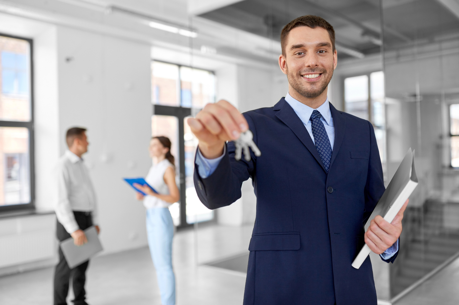 Smiling realtor with keys and folder at new office